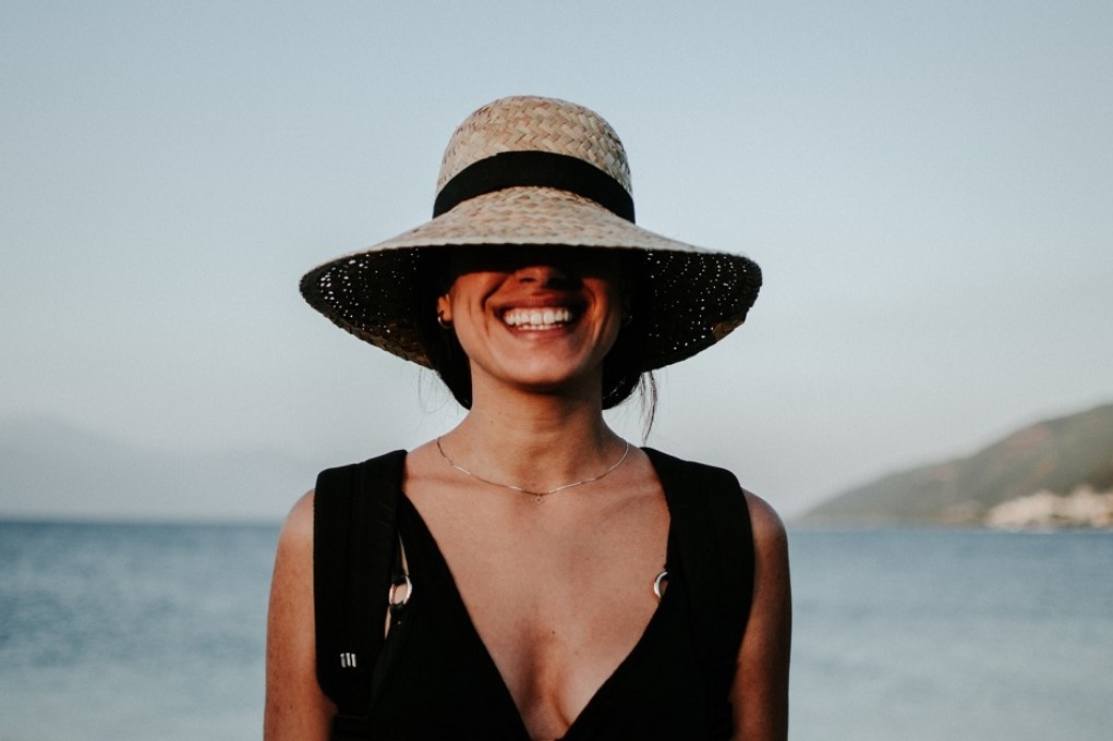 Lachende vrouw op strand met hoed