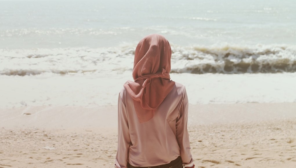 Vrouw kijkt uit over de zee vanaf het strand