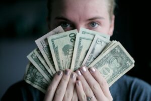 Vrouw houdt bankbiljetten voor haar gezicht